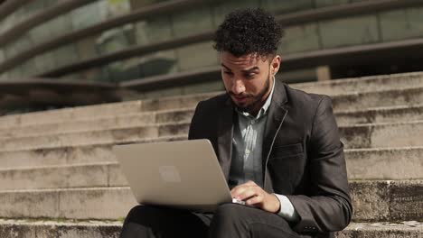 Tired-middle-eastern-young-businessman-working-with-laptop